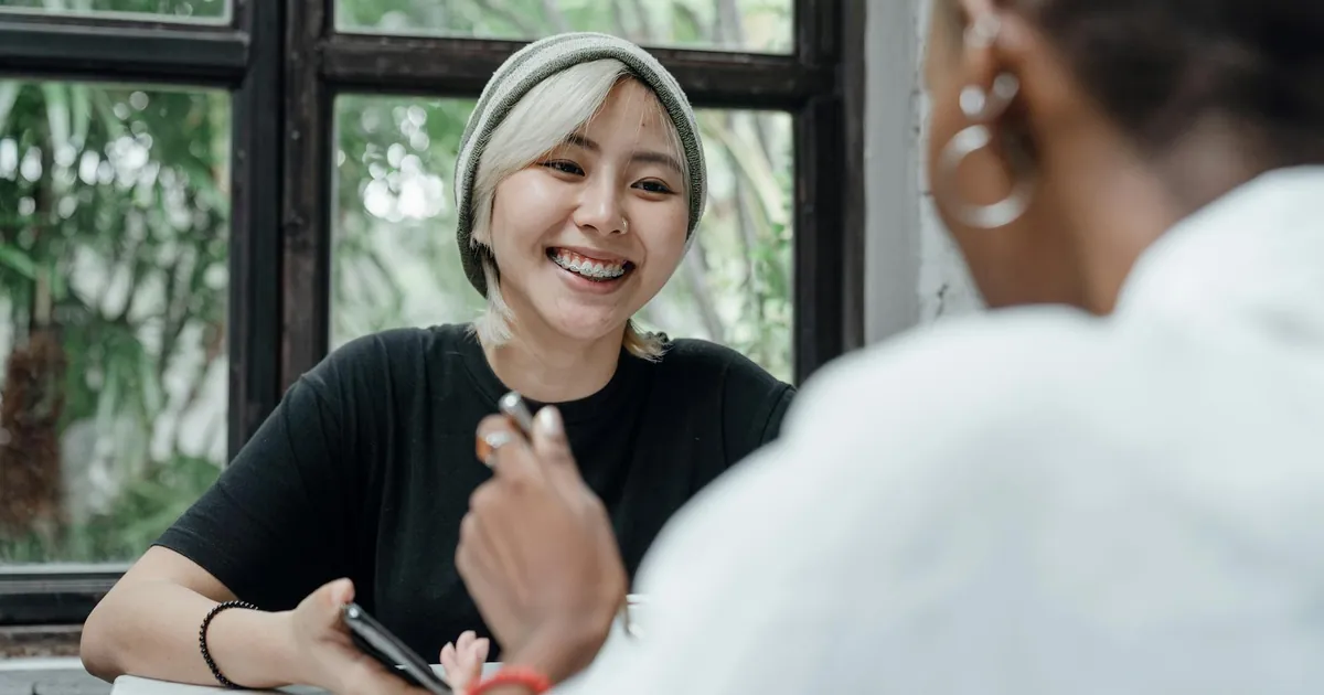 Two young women enjoy a lively conversation at a cafe.