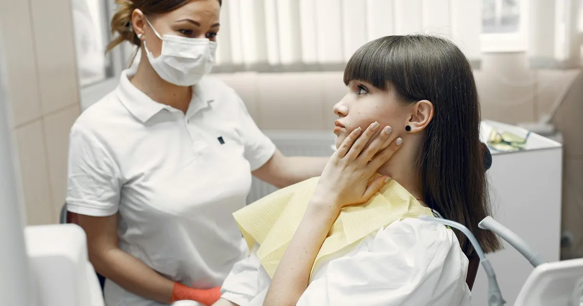 A dentist examining a young woman with toothache in a dental clinic.