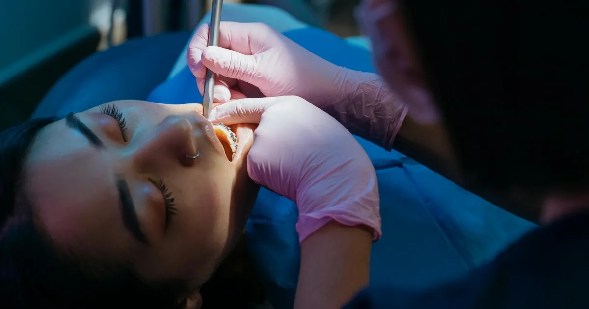 Dentist examines patient during a dental procedure with precision tools.