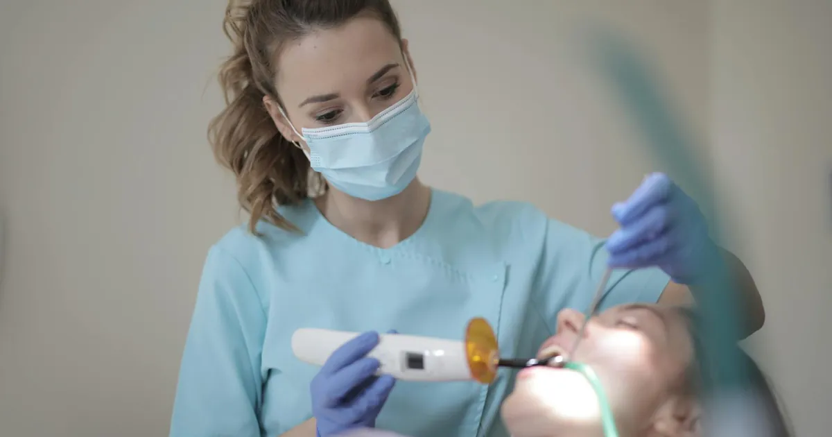 A female dentist using dental tools to treat a patient in a clinical setting.
