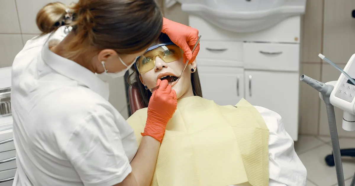 Professional dentist examines patient in a dental clinic with safety gear.