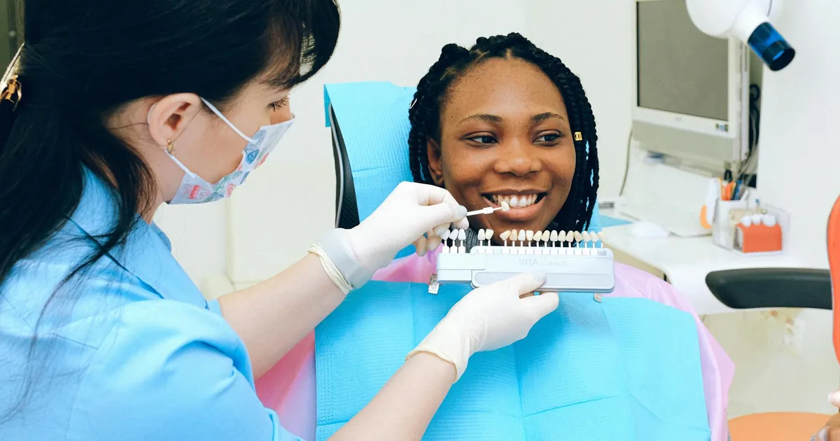Dentist consults patient with teeth color samples in a modern dental clinic.