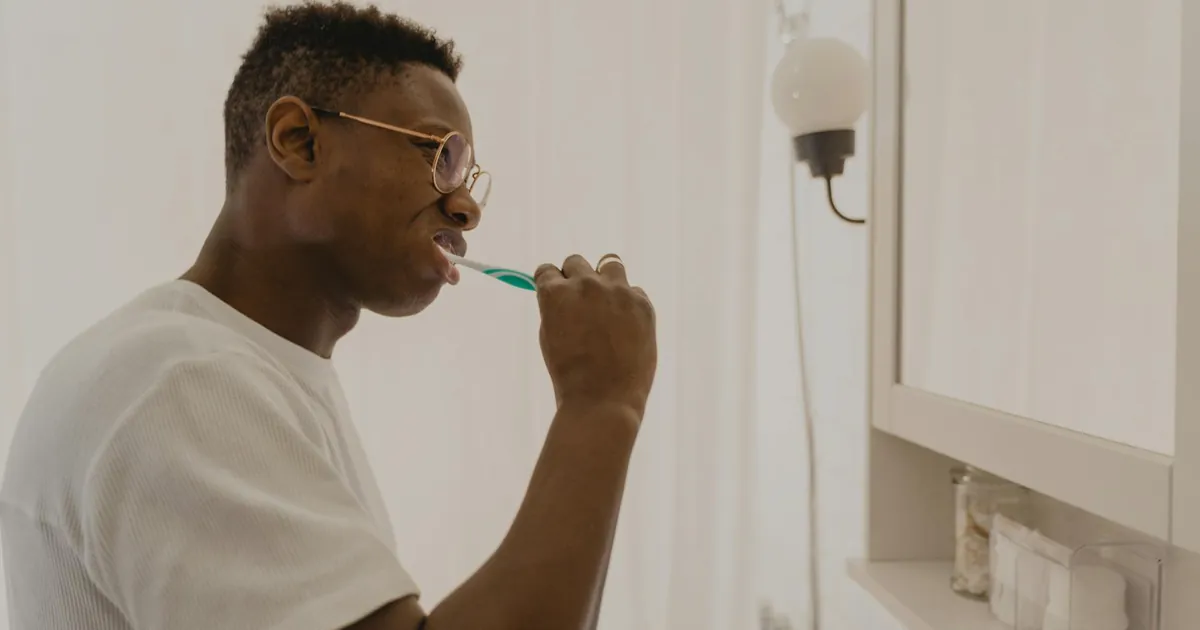 Man brushing his teeth in a bathroom, focusing on daily oral care and hygiene.