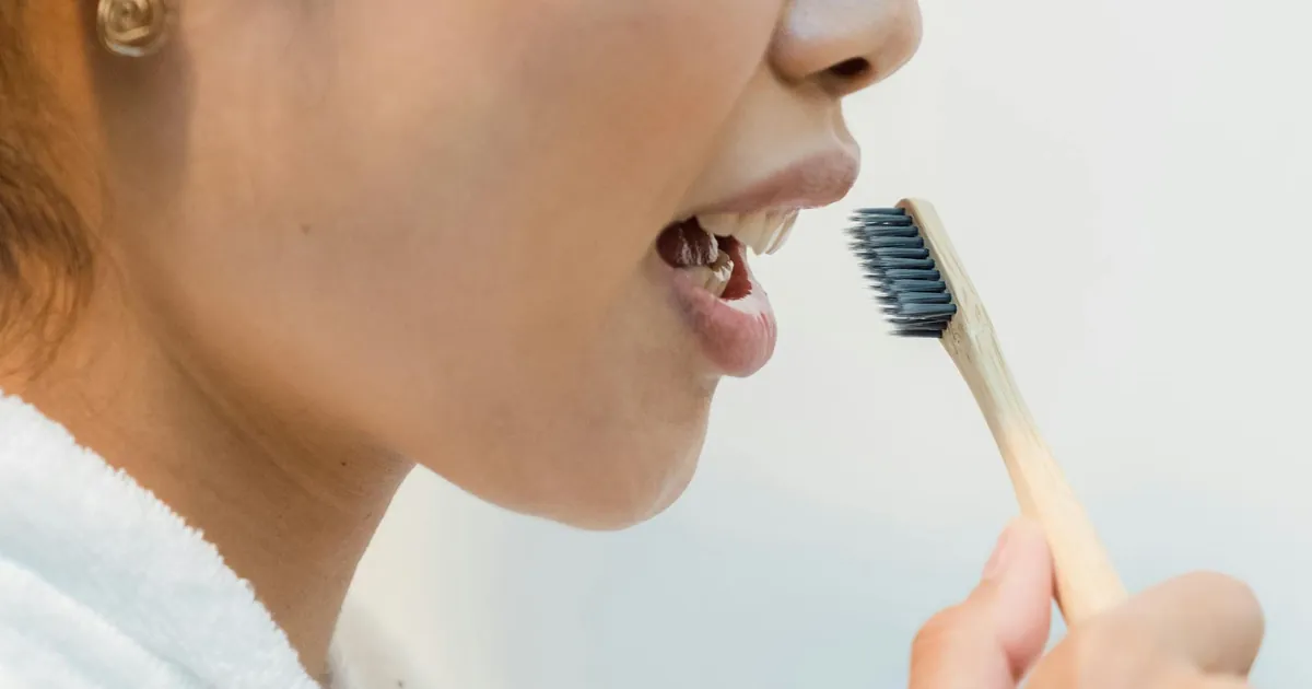 Close-up of a woman practicing oral hygiene with an eco-friendly bamboo toothbrush.