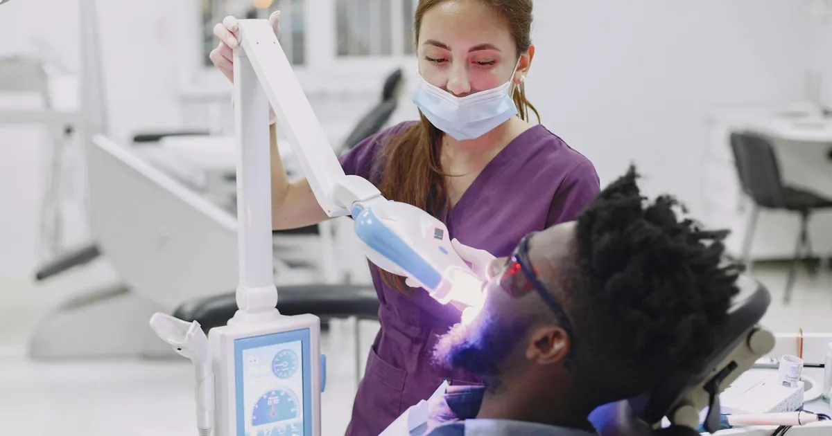 Dental professional using curing light during patient's checkup in a clinic.