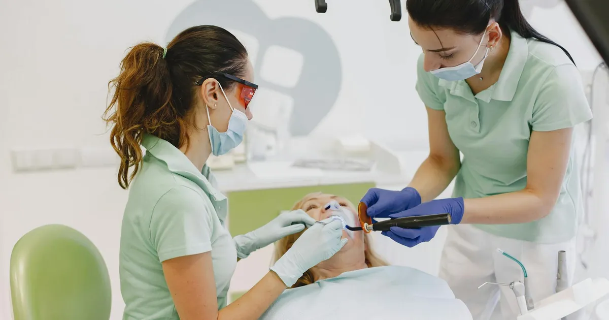 Dentists performing a dental procedure on a patient in a contemporary clinic.