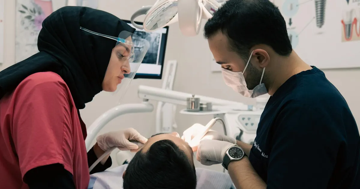 Dentist and assistant providing dental care to a patient with advanced equipment in a modern clinic.