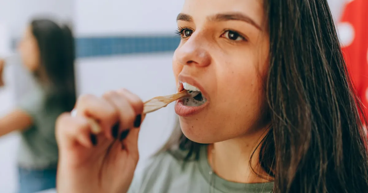 A woman brushing her teeth with a toothbrush