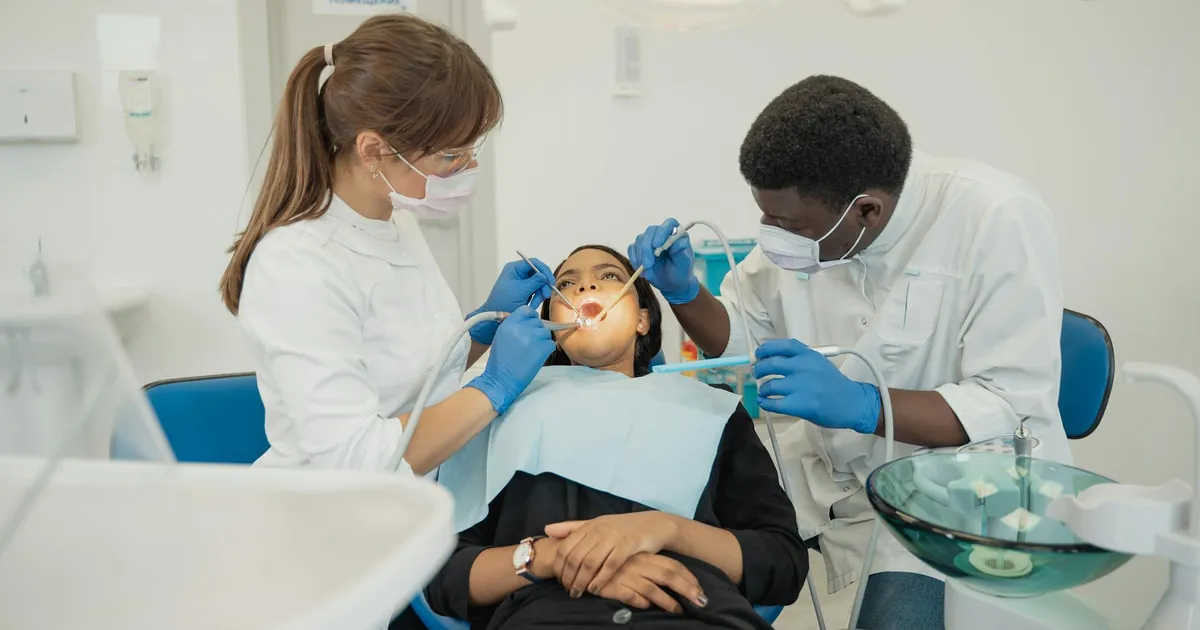 Two dental professionals treat a patient in a modern clinic setting.