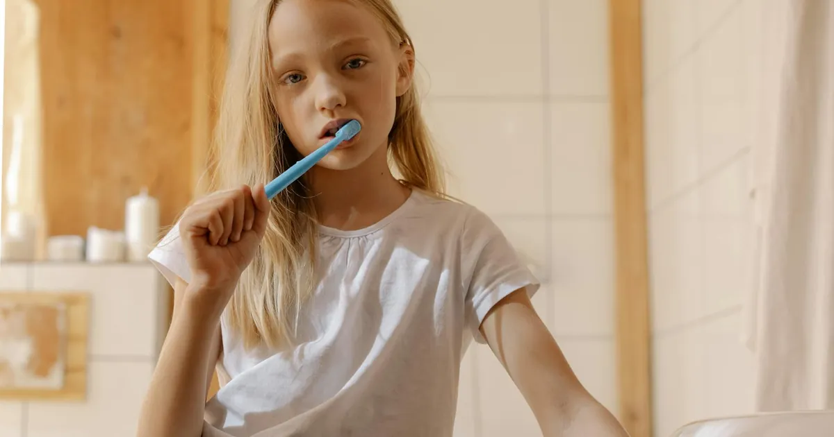 A young girl brushes her teeth, promoting daily dental care habits.