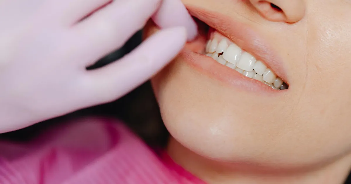 A dentist's gloved hand inspecting a patient's teeth during a check-up.