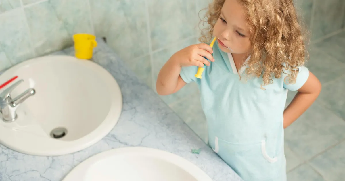 Child brushing teeth by sink, highlighting personal hygiene habits.