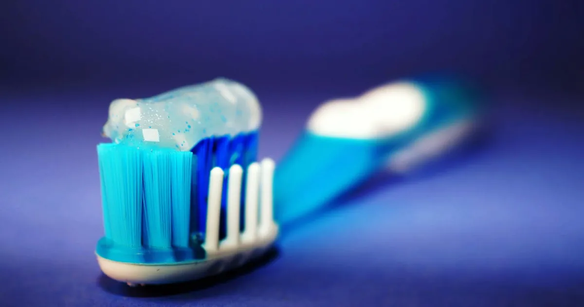 Macro shot of a toothbrush with blue toothpaste and blurred background.