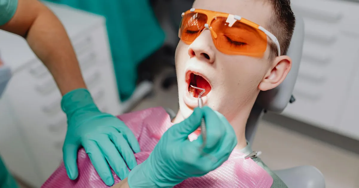 A patient receiving dental care while wearing protective eyewear in a clinic setting.